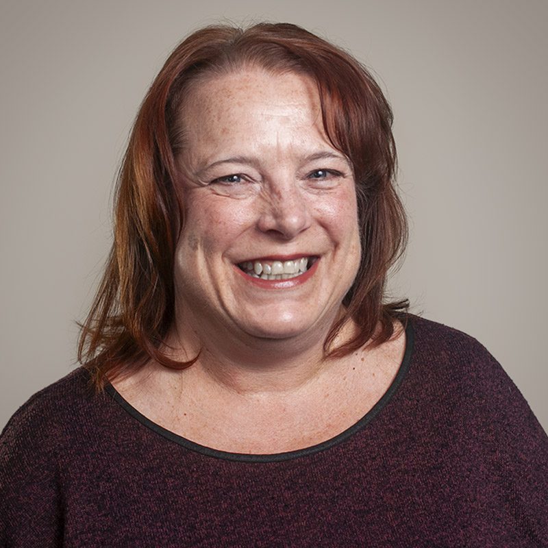 Image of Burkett CPAs Administrative Assistant Sandy Reilly, smiling, wearing a burgundy top