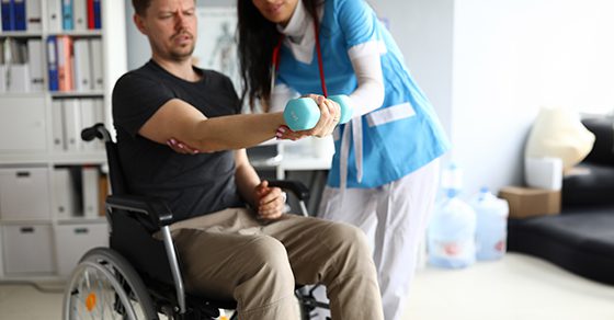 Man in wheelchair doing physical therapy with a nurse